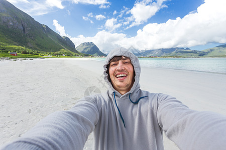 在洛福顿岛的拉姆贝格斯特兰达海滩上做自拍的旅游者 美丽的沙滩和凉水 挪威蓝天微笑假期天蓝色海滩幸福峡湾男人爬坡旅行图片