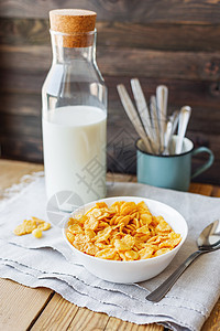 美味的玉米薄片和奶瓶放在碗里 有软木背景 有家庭餐巾 健康脆饼早餐点心勺子食物玉米片午餐饮食美食土布牛奶粮食桌子图片