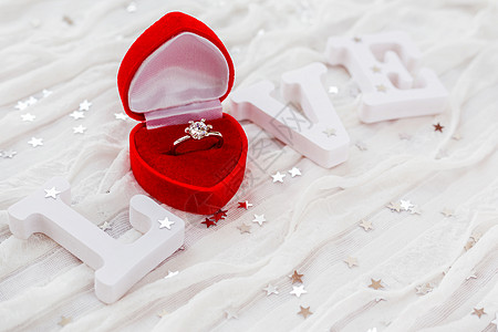 白布背景上的爱字 红礼盒中的订婚金钻环 对情人节的日卡很有帮助婚礼纸屑织物白色珠宝红色盒子火花展示钻石图片