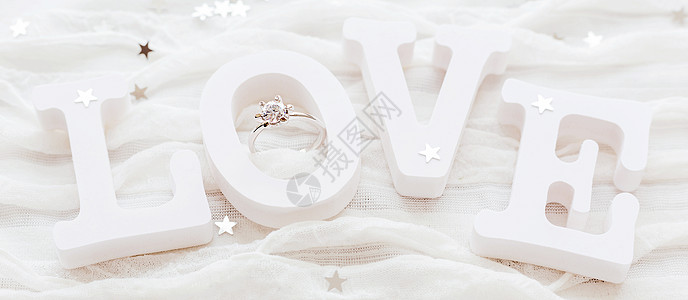 白布背景上的爱情和订婚钻石戒指 对情人节的日卡很有帮助 写短信的地方火花白色织物纸屑婚礼珠宝雪花婚姻星星图片