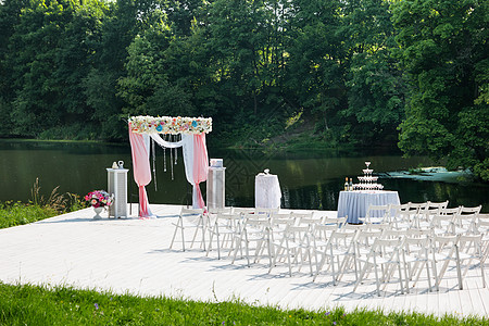 美丽的花岗拱门用于婚礼仪式 有粉红玫瑰和风味的花瓶 在池塘附近的公园外布置婚纱牡丹衬套日落植物群浪漫玫瑰配饰植物婚姻庆典图片