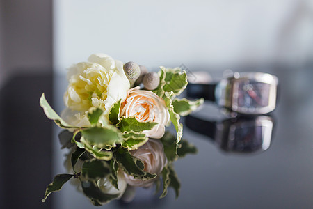 Boutonniere带着玫瑰花和手表躺在光滑的镜面上 是婚礼上新郎的传统帮凶之一图片