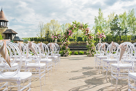 美丽的花岗拱门用于婚礼仪式 有粉红玫瑰和风味的花瓶 在池塘附近的公园外布置婚纱大厦植物庄园日落浪漫庆典玫瑰配饰牡丹植物群图片