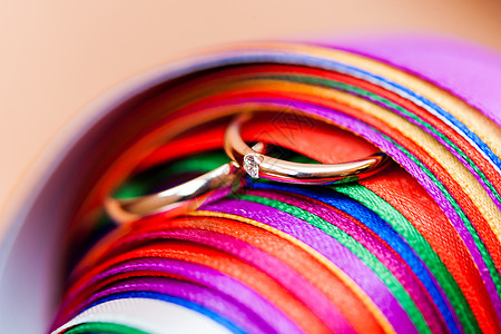 婚戒对齐的彩虹彩色丝带 钻石订婚戒指和多彩装饰品 并配有钻石宏观婚姻珠宝宝石夫妻图片