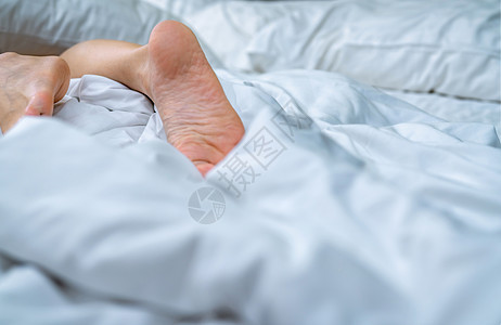 女人用白毯子和床 赤脚躺在床上男人女士羽绒被酒店卧室床单女性赤脚脚趾顾客图片