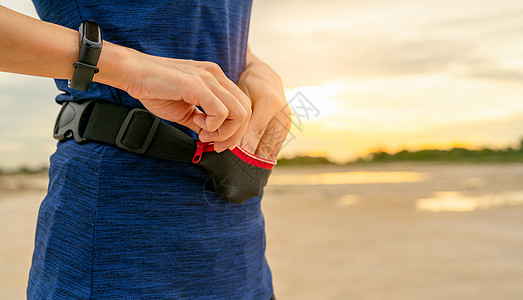 年轻亚洲女性在跑步前用腰包装智能手机电话技术速度乐队小袋锻炼有氧运动腕带赛跑者女孩图片