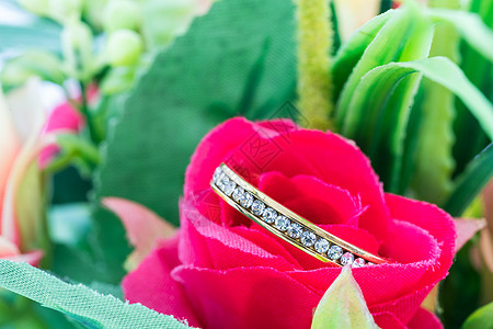 在假玫瑰花中安息的结婚戒指乐队念日珠宝庆典金子订婚玫瑰首饰钻石婚礼图片