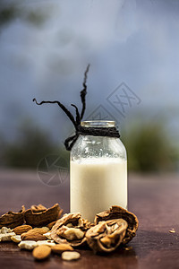 在一个粘土碗中的木质表面贴近胡桃或阿赫罗特 用一个小的透明瓶子做干果奶昔饮食食物水果乳糖奶制品早餐香草玻璃榛子坚果图片