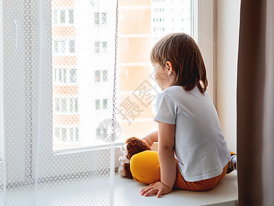 蹒跚学步的男孩坐在毛茸茸的刺猬身边 毛绒玩具的孩子看 t展示游戏疾病友谊男生婴儿卫生儿童封锁窗户图片