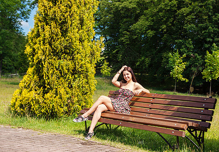坐在公园长椅上的女孩女士黑发幸福绿色微笑成人女性图片