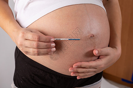 由妇女亲手进行阳性怀孕测试腹部白色生活新生母亲排卵父母激素家庭女士图片