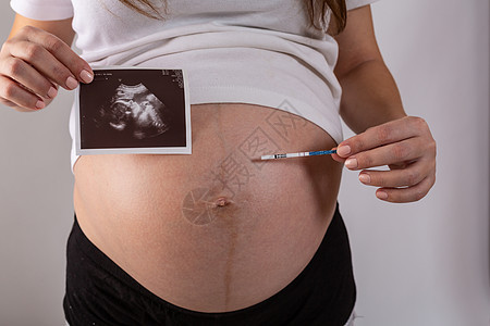 由妇女亲手进行阳性怀孕测试母亲惊喜腹部生育力女性女士成人婴儿排卵女孩图片