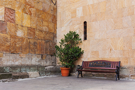 格鲁吉亚第比利斯Sioni大教堂附近有休息处 在石墙附近有座长椅和一棵满锅的树图片