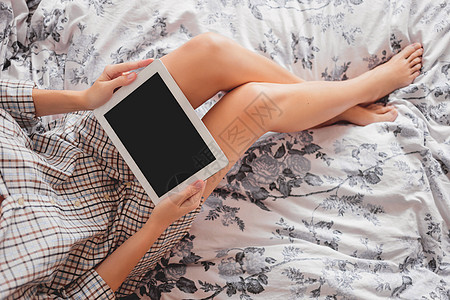 穿着格斗衬衫的女人和平板电脑一起坐在床上 在家睡得舒服点 用小工具睡觉图片