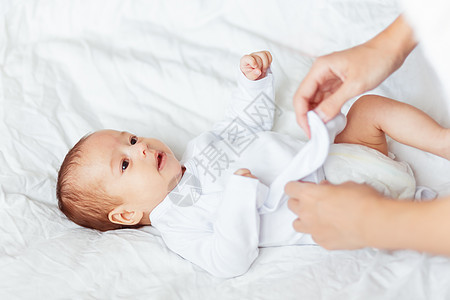 妈妈给孩子换衣服 女人为年幼的儿子或女儿更换紧身衣裤父母家庭新生卫生舒适母亲尿布白色衣服女士图片