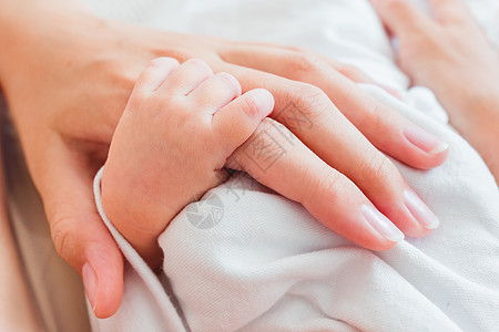 新生婴儿握着母亲的手指 幼小婴儿和成年妇女的手 温柔的时刻父母皮肤女孩母性孩子压痛妈妈女士投标成人图片