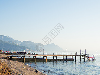 清晨在海滩上 典型的土制酒店 有日间休息员和木质浮游艇 土耳其凯默地平线阳光沙滩领土卵石码头太阳椅旅游露天浮桥图片