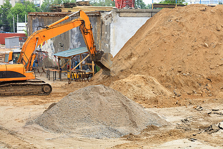 在修建公路和一座新的多层楼期间建造重型建筑挖土机时使用的挖掘机施工橙子工人推土机振动机器机械柴油机地面构造图片