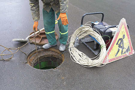 该雇员在街道上打开了舱门 以消除紧急情况 紧急事件工具安全行动工作服维修服务沥青下水道地面工人图片