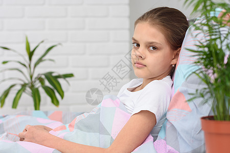 一个女孩躺在床上 看着框架的肖像图片