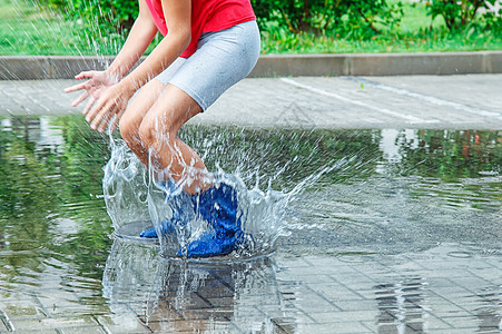 女穿橡胶靴的女孩在雨后跳进水坑图片