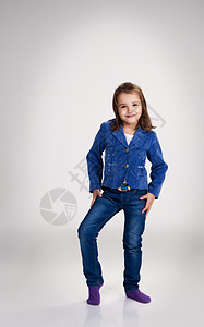 穿着蓝色牛仔裤和外套的小女孩 在工作室摆布冒充夹克孩子魅力女孩站立卷曲童年女性图片