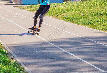 青年女子在公园滑板城市女性爱好乐趣晴天运动潮人牛仔裤骑术女孩图片