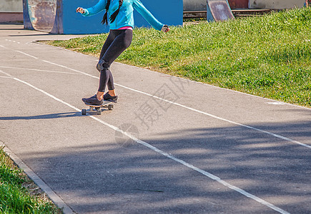 青年女子在公园滑板女孩女性成人乐趣滑冰城市溜冰者女士骑术牛仔裤图片