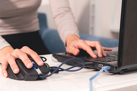 在笔记本电脑上工作的妇女手在使用USB鼠标图片