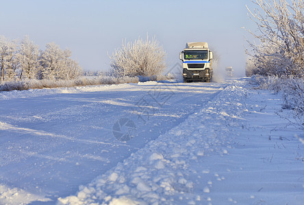 一辆重型卡车车队沿一条雪白公路行驶图片