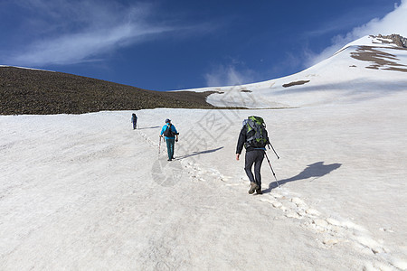 游客们从山坡上爬到雪顶顶顶峰图片