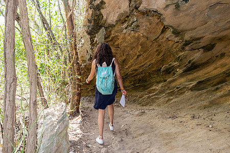 女人在一块大岩石下行走雕塑小路海岸旅游洞穴目的地旅行隧道砂岩荒野图片