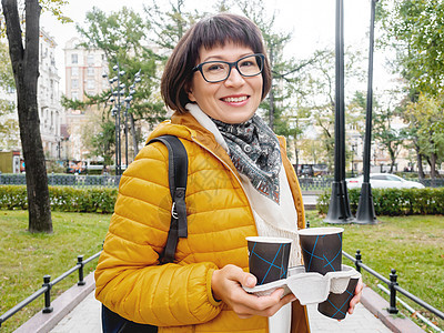 带着咖啡 快乐地欢乐着微笑的女士们学生饮料眼镜游客旅行女士笑容纸板旅游杯子图片