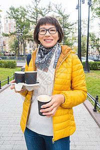 带着咖啡 快乐地欢乐着微笑的女士们杯子眼镜旅游夹克咖啡杯学生公园阳光女士情感图片