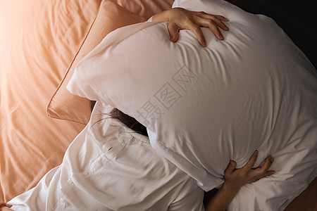 睡不着的女人躲在枕头下 讨厌早起压力隐藏铃声时间女性唤醒卧室噪音毯子就寝图片