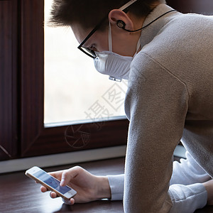 一个戴医用面具的年轻人看着电话屏幕获取信息呼吸消毒剂警告细菌疾病灰尘药品口罩社区卫生图片