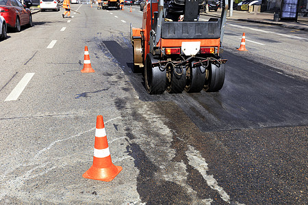 红色公路连接一条路段和市街上滚滚路面的红锥形道路背景图片