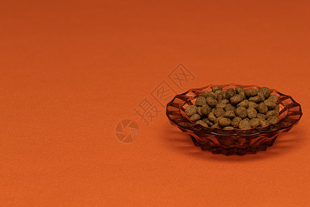 橙色背景中美丽碗里的猫食球孤立图片