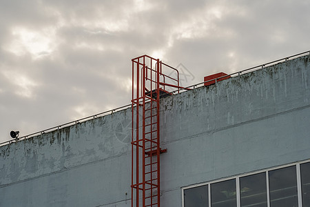 红色火警逃至建筑物屋顶的红色防火梯工业领导安全出口建筑学技术金属脚步蓝色栏杆图片