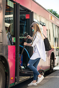 乘坐可折叠电动城市踏板车进入城市公交车的少女通勤者 在 covid-19 大流行时戴着防护面罩 防止冠状病毒传播和疾病传播图片