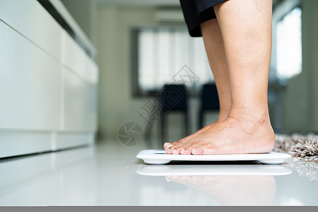 老年妇女在起居室中按重量级站立房子测量女性运动脚趾数数药品重量乐器房间图片