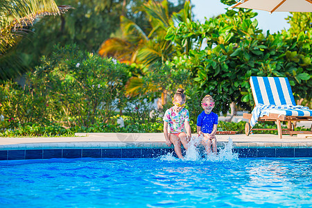 母亲和小女儿的家庭在豪华游泳池中享受暑期假期父亲日光浴女孩热带成人娱乐父母太阳镜黑发乐趣图片