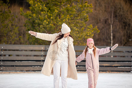可爱的小女孩 她妈妈在冰加冰上溜冰滑冰母亲喜悦训练娱乐乐趣闲暇女儿女孩帮助图片