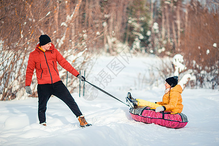 父亲和孩子的家人在圣诞节前夕户外度假骑术围巾季节管子雪花家庭父母女孩闲暇幸福图片