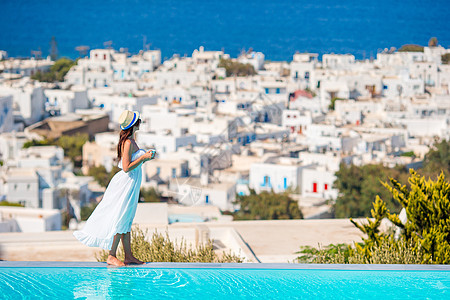 快乐的女士在游泳池边缘放松 在希腊Mykonos的景色令人惊叹图片