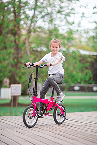 在美丽的夏日露天户外 骑自行车的可爱女孩训练游戏公园幼儿园踏板速度快乐人行道幸福乐趣图片