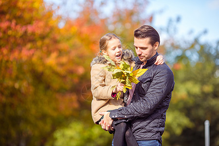 父亲和孩子的家庭 在美丽的秋天在公园里幸福金子男人季节森林天气女孩父母婴儿树叶图片