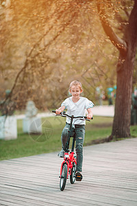 在美丽的夏日露天户外 骑自行车的可爱女孩幼儿园踏板训练快乐运输季节公园乐趣童年游戏图片