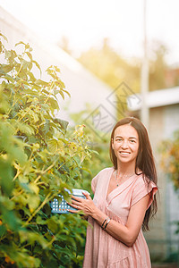 在温室里拿着一篮绿菜和洋葱的年轻女子农场收获叶子女士饮食植物微笑收藏萝卜食物图片