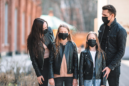 在现代建筑背景上戴面罩的一家人街道孩子感染疾病城市父母口罩手术空气流感图片
